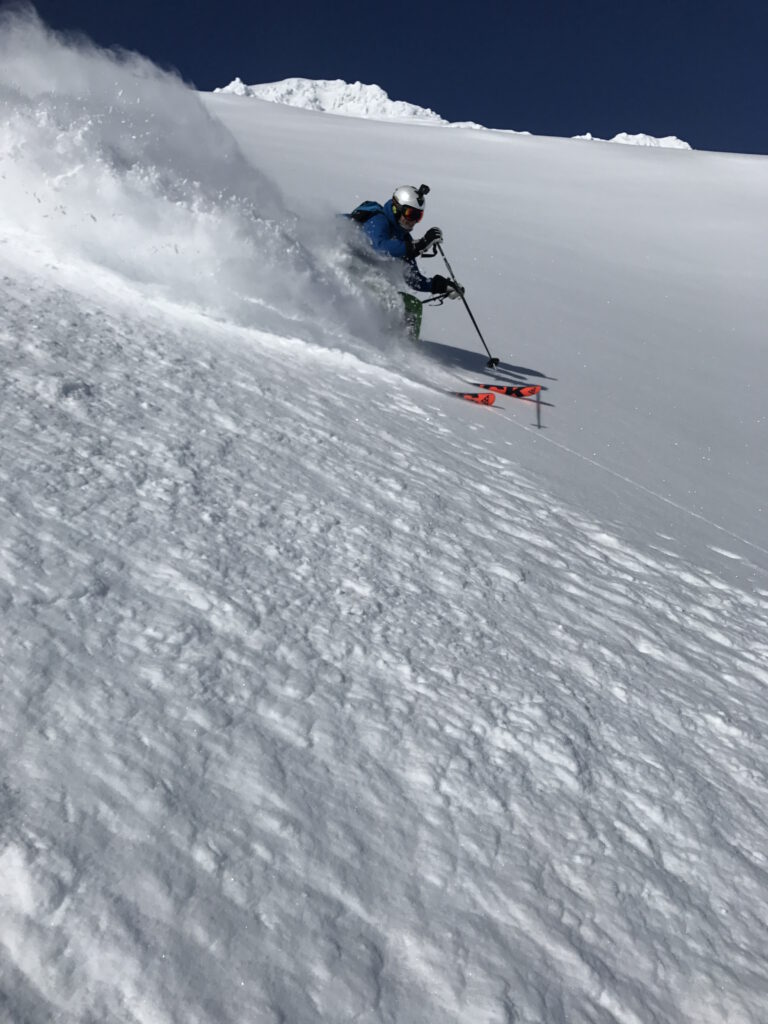 Man on slalom skis heading down the mountain and the snow swirling