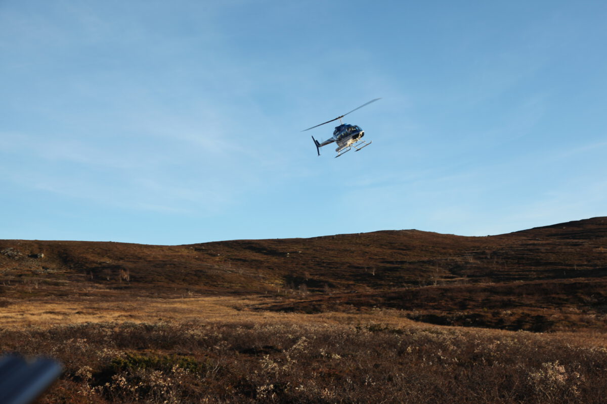 A flying helicopter in the sky with mountain peaks on the horizon